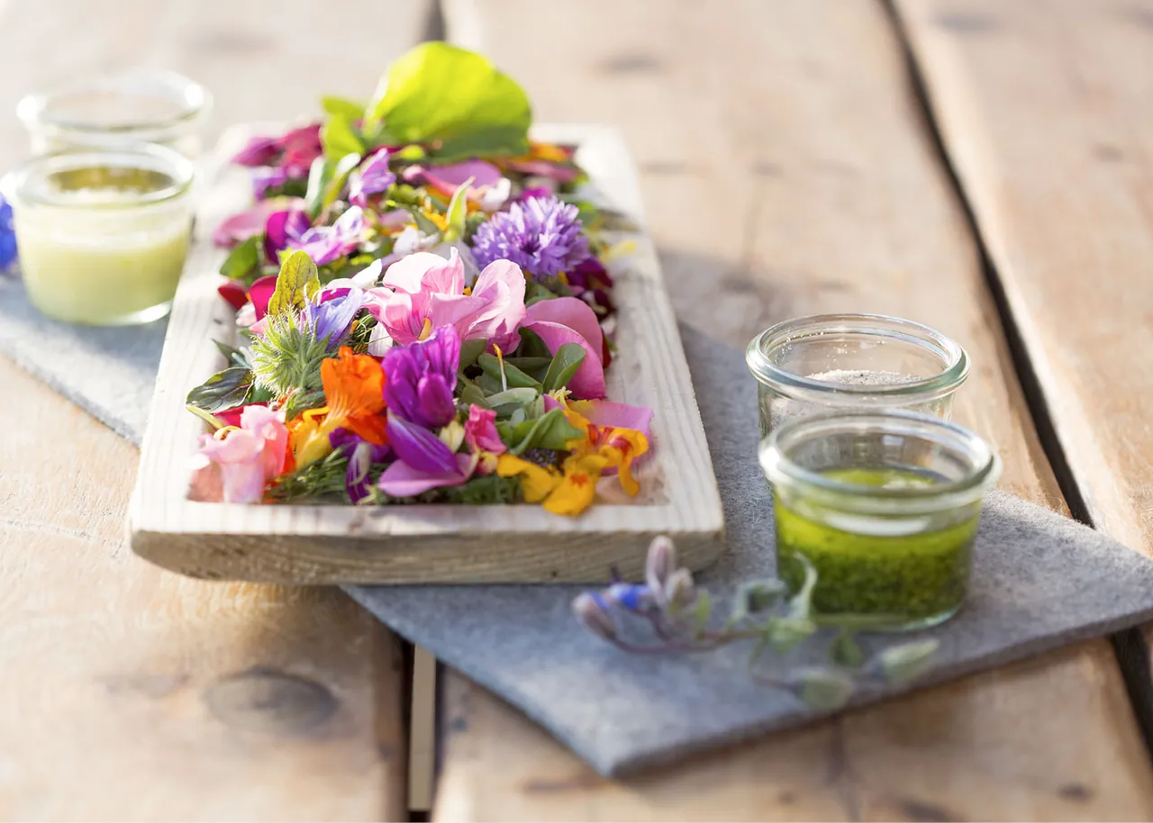 Blumensalat mit Kräuterdips auf dem Holzbrett