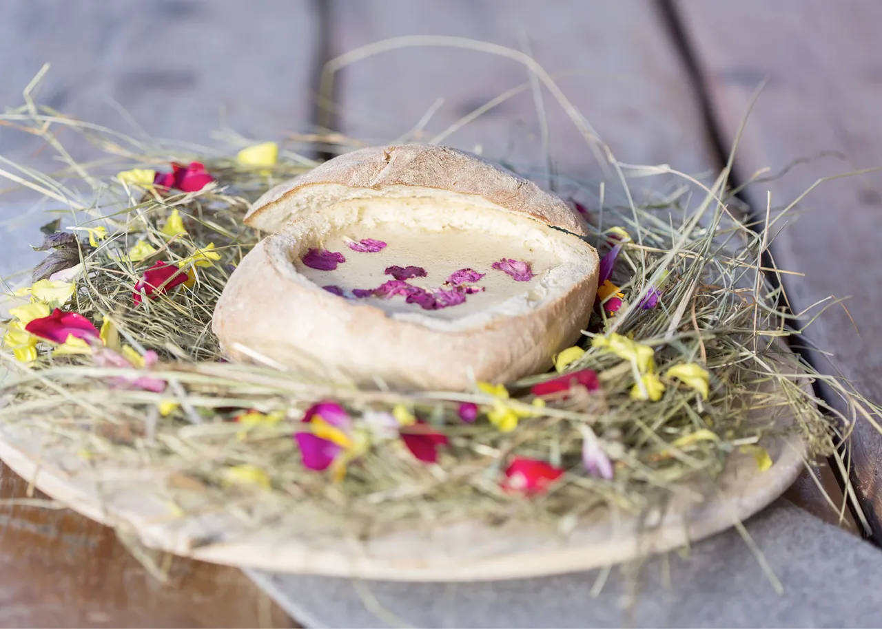 Heublütensuppe im Brottopf auf Heu und Blüten